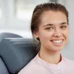 smiling young woman in dental chair 38CBRJM min