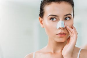 attractive young woman applying nose strip in bath 2N7AP8G min