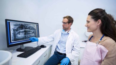 dentist showing an x ray of teeth to female patien UPJJEWM min scaled min