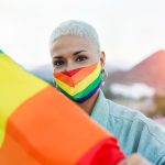 Beautiful latin lesbian woman with LGBT pride rainbow flag outdo